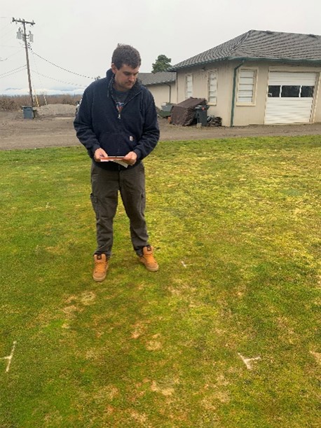 a person outside with a notebook in their hands looking at diseases turfgrass research plots