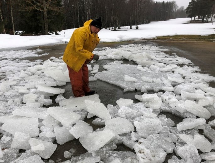 a man standing amid broken sheets of ice on a golf course