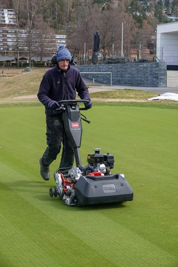 a person mowing a golf course green